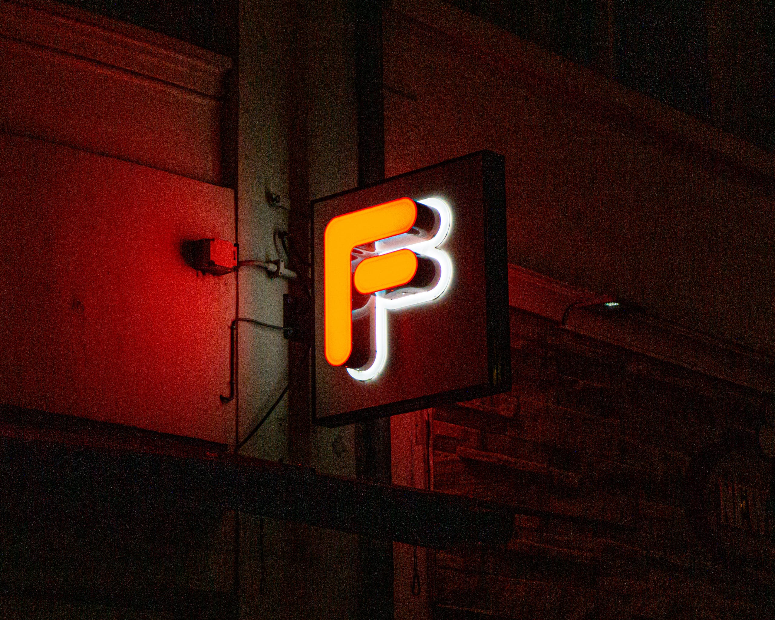 Red neon sign on a brick wall at night